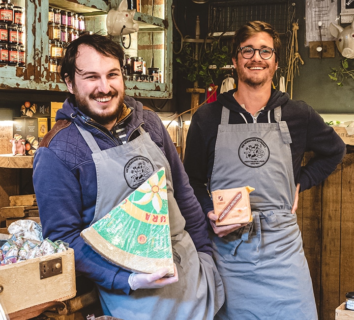 Two cheesemongers holding cheese