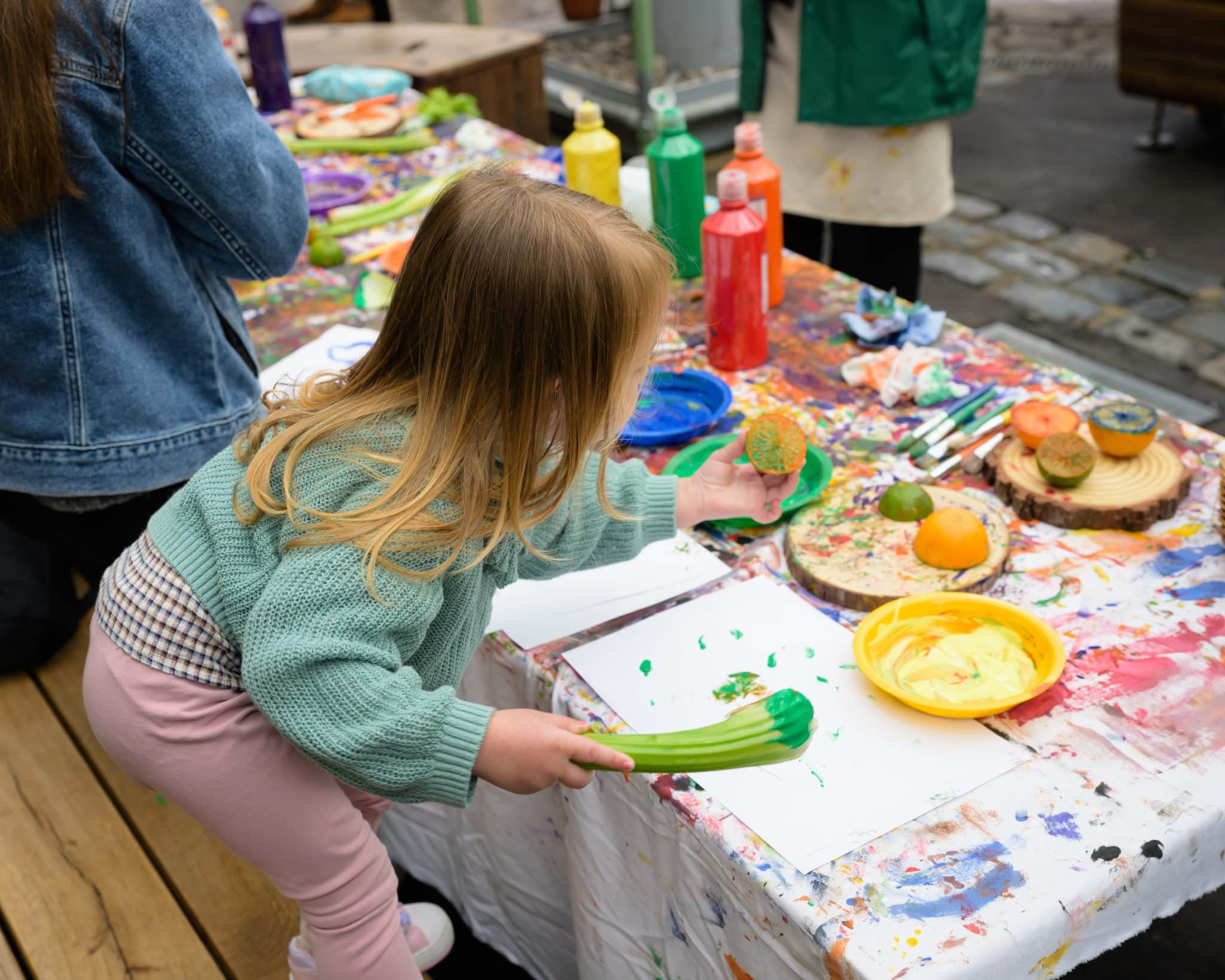 A child painting with vegetables at the Market Explorers Garden
